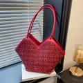 Red woven tweed tote bag with V-cut design and slim leather handles on a white book - Red