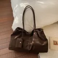 Grande borsa tote marrone scuro scamosciata con pochette abbinata sul letto - Marrone
