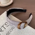 Grijze corduroy gevoerde hoofdband met amberkleurige harsring op een houten vintage tafel - Grijs