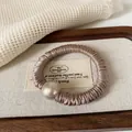 Coletero elegante de satén champán con gran perla dorada para coletas de mujer - Coletero de Perlas Caqui