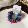 Blauwe denim scrunchie met rood gingham kant op een wit keramisch bordje gepresenteerd - Lichtblauw Rood Geruit