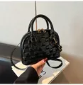 Macro detail of black crocodile shell bag showing shiny finish and golden metal zipper - Black