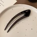 Minimalist black U-shaped hair pin with gold logo lettering on premium resin surface - Black U-Shaped Hair Fork