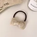 Elastic black hair tie featuring a pearlescent white bow charm for elegant styling - Pearlescent White