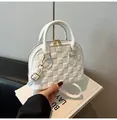 Detail of white shell handbag featuring checkered embossing and golden hardware accents - White