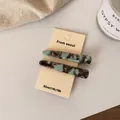 Brown and mint green marble acetate hair clip set on a cream display card - Black Green