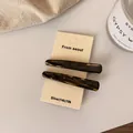Pair of retro acetate striped hair clips with brown tortoise shell pattern on display card - Black