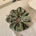Dark green plush velvet scrunchie with soft texture and white AY jewelry fabric label - Green