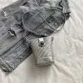 Silver woven texture crossbody phone bag with round metal buckle on denim background - Silver