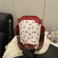 White cherry print bucket bag with red trim and wide geometric woven shoulder strap - Red