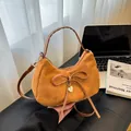 Caramel suede crescent tote bag with bow detail and heart pendant on a window sill - Brown