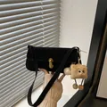 Black suede baguette underarm bag with gold oval lock and plush monster charm - Black