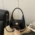 Bolso de mano minimalista en charol negro con hebilla dorada y correa ajustable - Negro