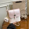 Rosa und beige Umhängetasche mit Schleifen-Print und Herzverschluss in der Hand - Mit Anhänger / Rosa