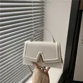 Elegante bolso de mano blanco con hebilla en V dorada y correa ajustable - Blanco