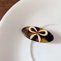 Tortoiseshell resin hair clip with cream bow and amber rhinestone in a ceramic dish - Dark Tortoiseshell Oval Clip