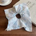 Floral scrunchie in light blue fabric with white lace trim on a wooden table - Blue Flower
