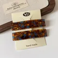 Two tortoiseshell acetate hair clips in brown and blue, secured on a display card - Blue-Brown