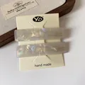 Set of two rectangular pearlescent acetate hair clips in elegant purple grey on a card - Mermaid White