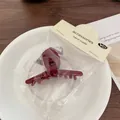 Deep red acetate hair claw clip with golden lettering in retail packaging - Red Cross Claw