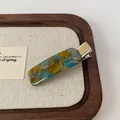Elegant acetate hair clip featuring a blue and yellow marble pattern with gold text detail - Blue Grey Duckbill Clip