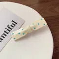 Molletta per capelli color crema a pois blu a forma di fiocco su un piatto bianco - Bianco avorio
