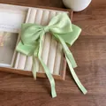 Elegant light green satin bow hair clip with long ribbons on a wooden tray - Green