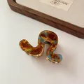Pinza de pelo ondulada en carey ámbar y azul con dientes metálicos dorados sobre blanco - Pinza Azul Marrón