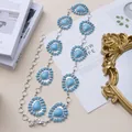 Catena da vita bohémien in turchese con ciondoli a girasole argentati su sfondo bianco - Cuore blu