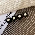 Minimalist black floral acetate hair clip with four flowers and creamy white centers - Black