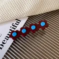 Floral acetate hair clip with four dark red petals and sky blue center accents - Burgundy