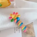 Colorful knitted flower hair clip with a yellow smiley face on a spiral resin base - Sunflower
