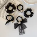 Five-piece black hair scrunchies set with pearls, lace, and bows on white desk - Pearl Lace Bow Combination