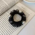 Elegant black lace hair scrunchie with large white pearls on a vintage book - Lace Pearl Style