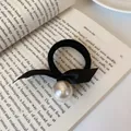 Elegant black silk bow hair tie with a large white pearl bead on vintage book background - Pearl Bowknot Style