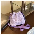 Detail of purple floral bucket bag with drawstring closure on dark wooden surface - Purple