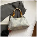 Bolso azul con bordado floral y asas de cuentas de madera en un fondo minimalista - Verde