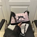 Pink pleated underarm bag with black bow prints and metallic heart pendant detail - Pink