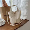 Beige lychee pattern bucket bag with smiley charm and adjustable shoulder strap - Off-white