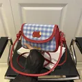 Blue plaid crossbody bag with red leather trim and apple embroidery on a book - Red