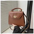 Detalle del bolso de cuero marrón con cierre rectangular dorado y asa superior suave - Marrón