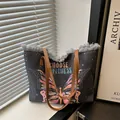 Deep grey canvas tote bag with butterfly print and frayed edges shown in a cozy setting - Black