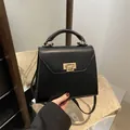 Classic black leather handbag with a rectangular gold twist lock and crossbody strap - Black