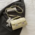 Bolso Boston beige tipo almohada con hebillas metálicas y colgante de lazo de perlas - Con Colgante / Amarillo