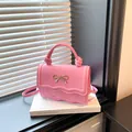 Pink crossbody bag with wave edge lid and golden bow charm on a minimalist background - Pink