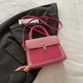 Hot pink structured crossbody bag with gold buckle and textured flap on blazer background - Fuchsia