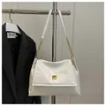 Close-up of white leather shoulder bag with gold buckle on a metal hanger - White