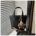 Chic black embossed bucket bag featuring a trendy plush monster charm and top handles - With Pendant / Black