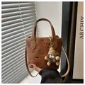 Brown bucket bag with SMNL embossing, plush dog charm and adjustable shoulder strap - With Pendant / Brown