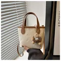 Cream bucket bag with brown handles and cartoon embossing featuring a plush monster charm - With Pendant / White